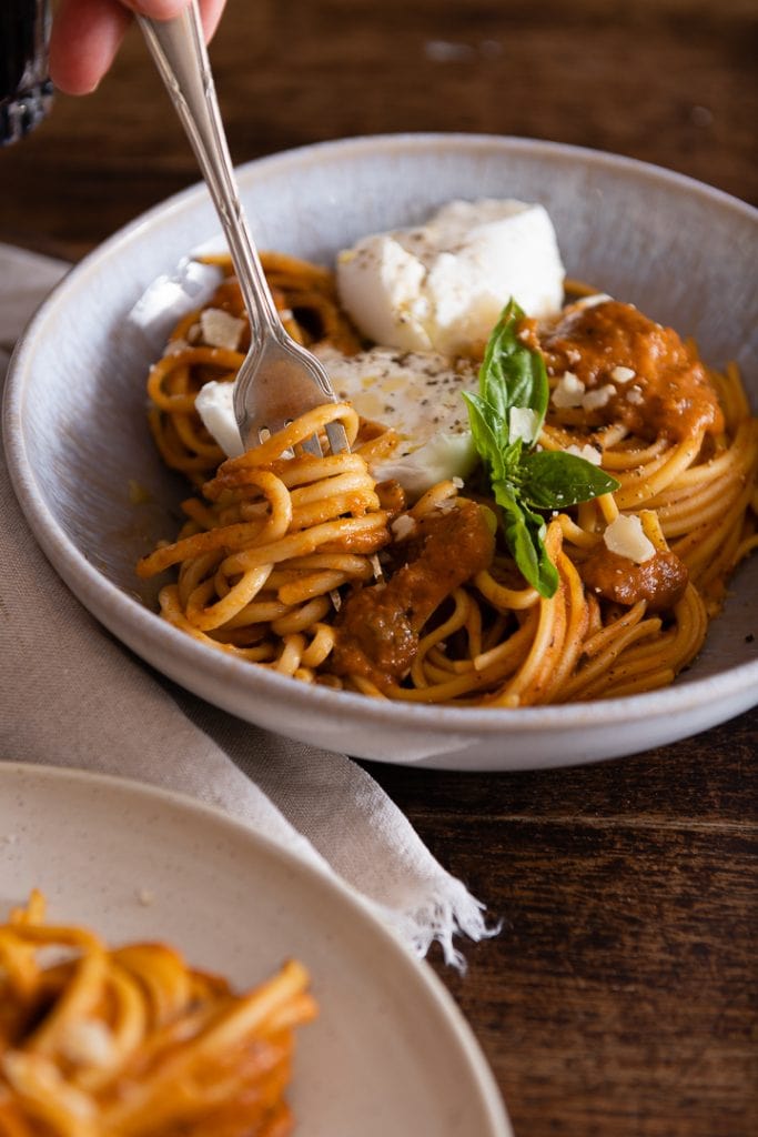 Eine Gabel nimmt pasta mit buntem gemüse.