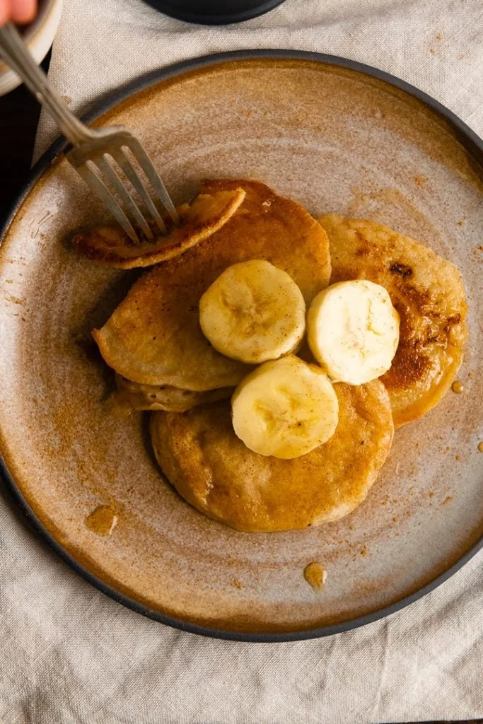 Eine Gabel nimmt ein Stück des Bananen Pancakes ohne Ei.