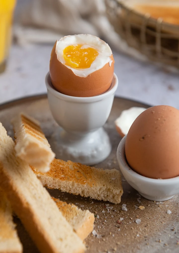 Ein weich gekochtes Ei als Frühstücksrezept mit ein paar Toastbrotscheiben.
