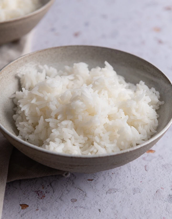 Ein Schüssel mit gekochtem Reis auf einem Tisch.