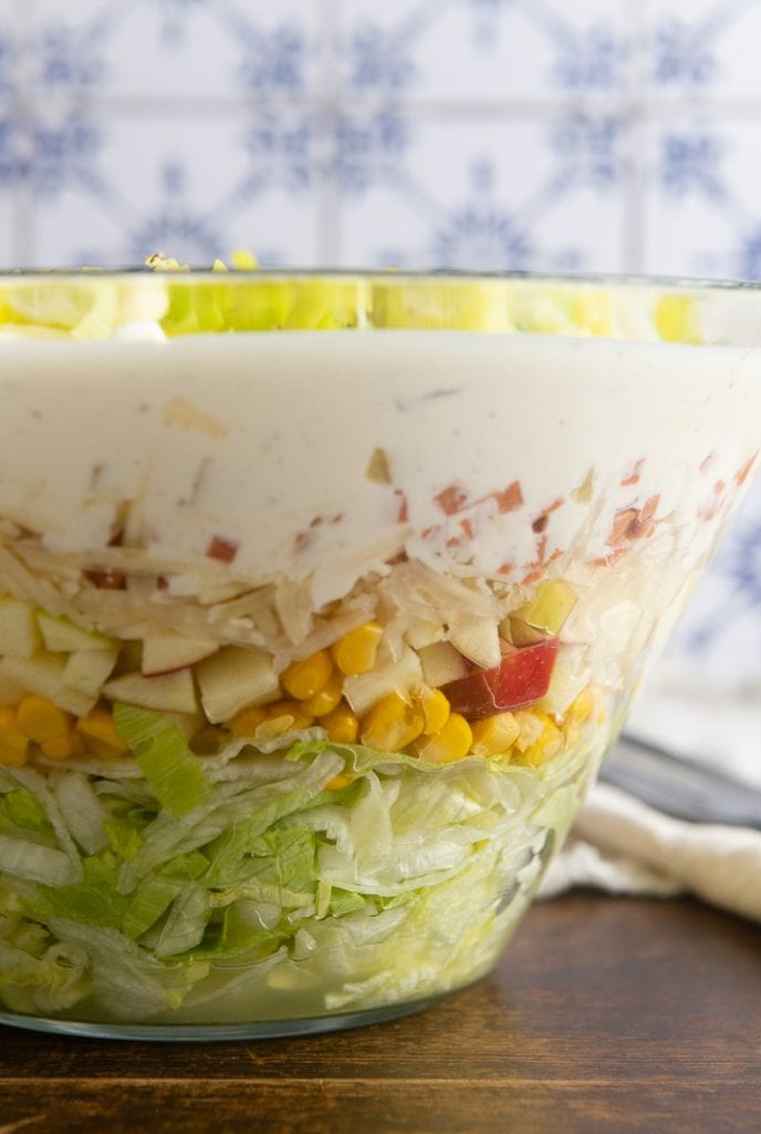 Ein vegetarischer Schichtsalat mit Eisbergsalat von der Seite, man sieht jede Schicht.

