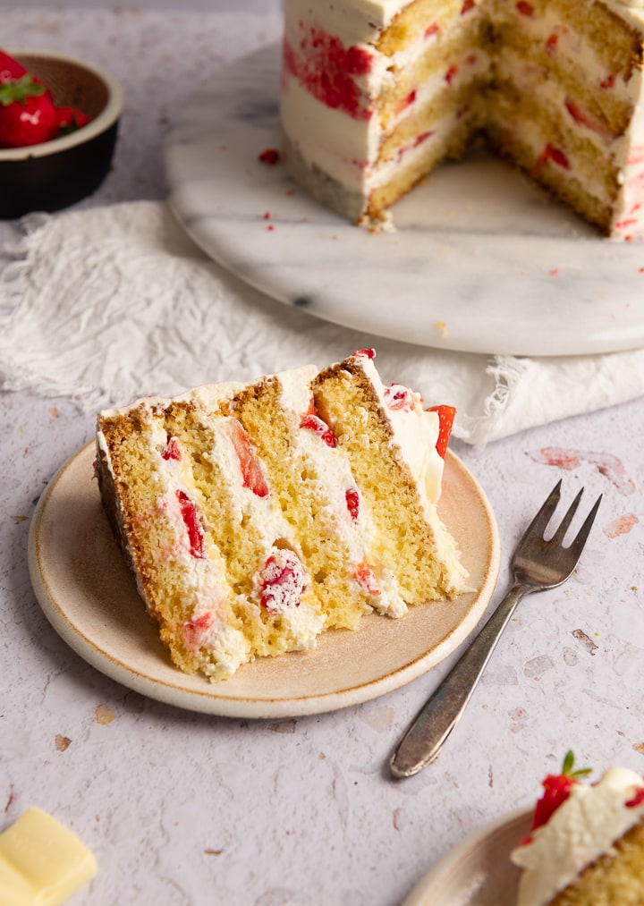 Ein Stück der Erdbeer Mascarpone Torte auf einem Teller mit einer Kuchengabel daneben.