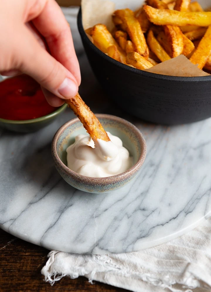Eine Pommes taucht in Mayo ein.