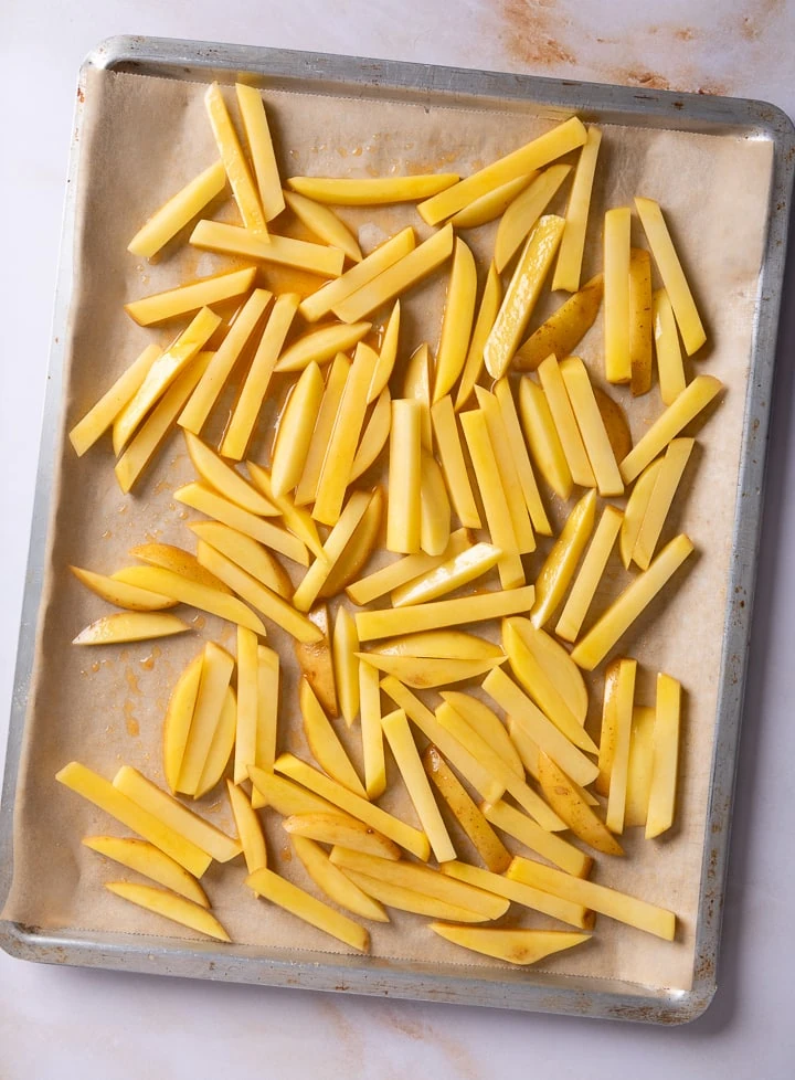 Die Kartoffel zu Pommes geschnitten auf einem Backblech.