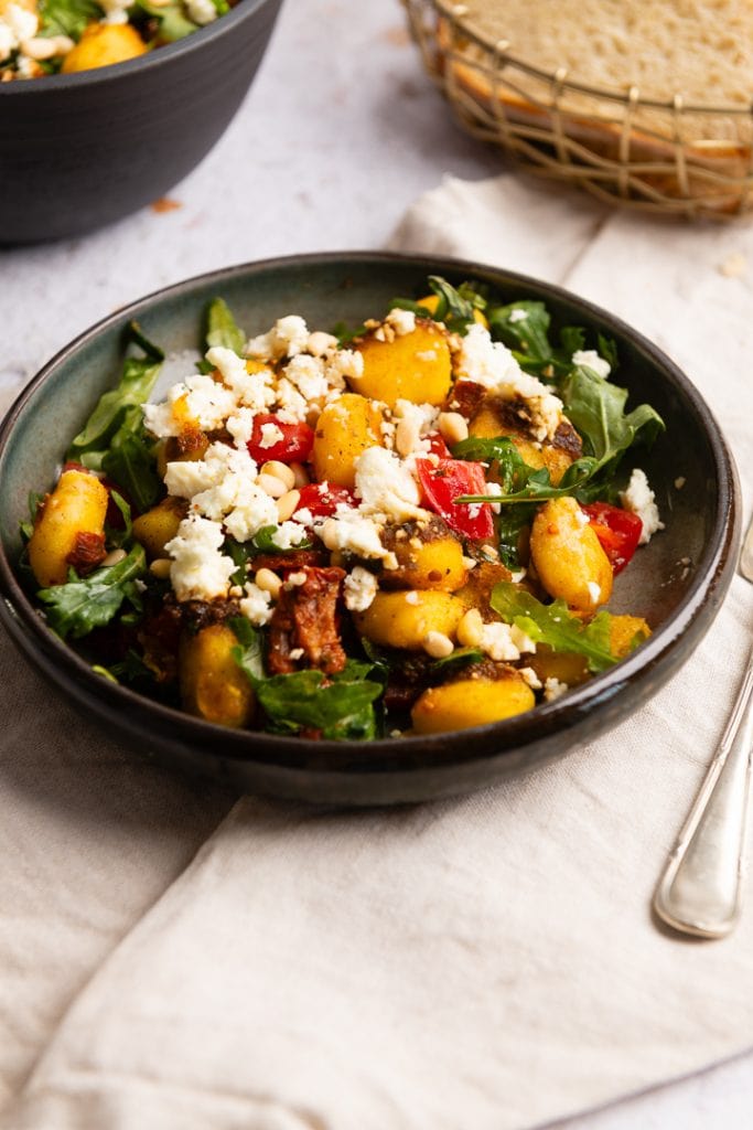 Ein Teller Gnocchi Salat auf dem Tisch, mit einer Gabel daneben.