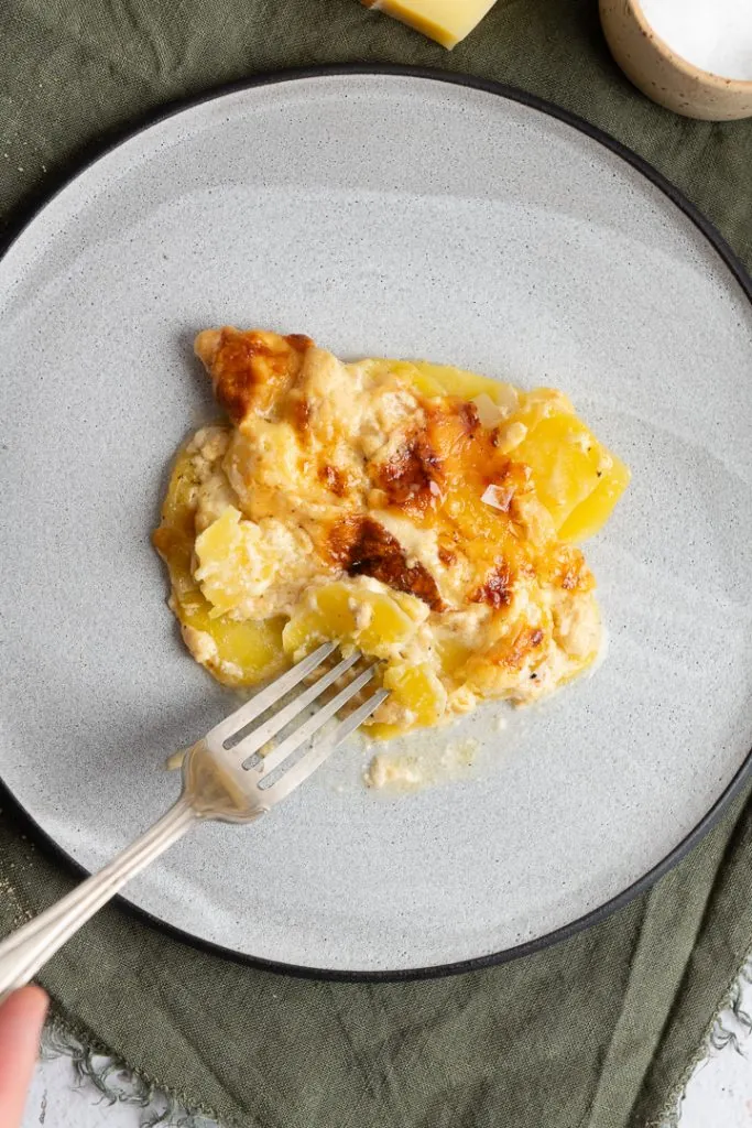 Etwas von dem Kartoffelgratin wird mit einer Gabel aufgenommen.