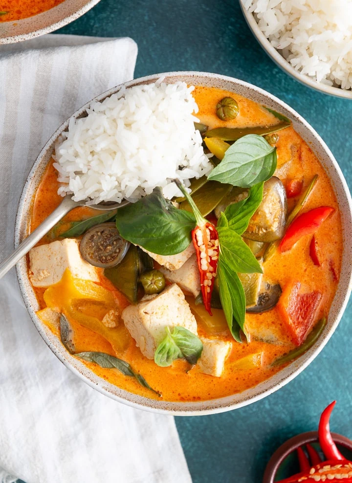 Ein rotes Thai Curry in einer Suppenschüssel mit Löffel.