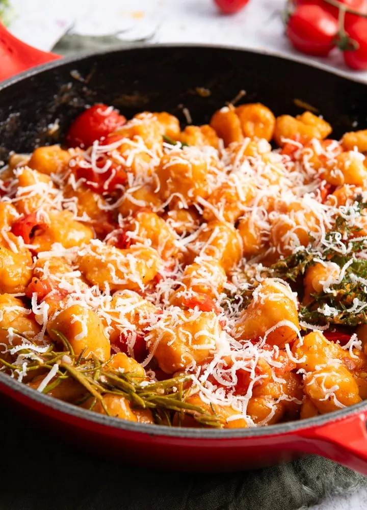 Die fertigen Süßkartoffel Gnocchi mit Tomaten und Parmesan in einer Pfanne.