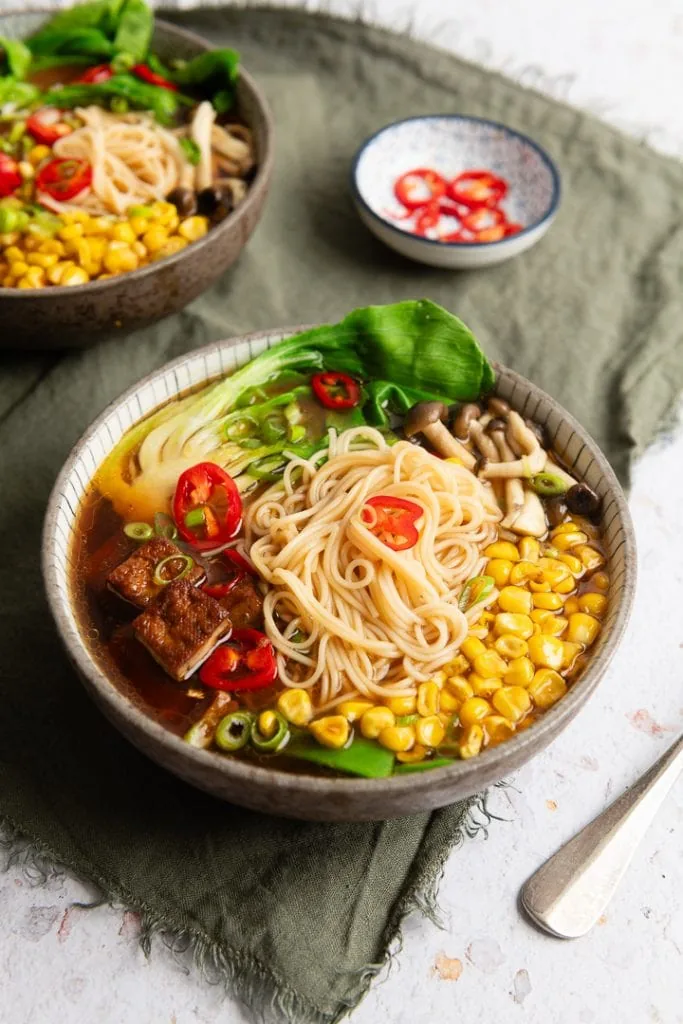 Auf der Ramen Suppe liegen Mais, Tofu, Chili, Nudeln und Pak Choi