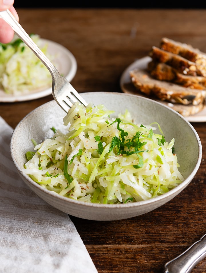 Original griechischer Krautsalat in der Schüssel, eine Gabel nimmt etwas auf.