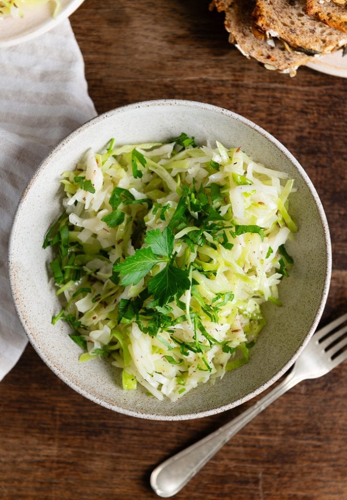 Griechischer Krautsalat in einer Schüssel, daneben liegt eine Gabel.