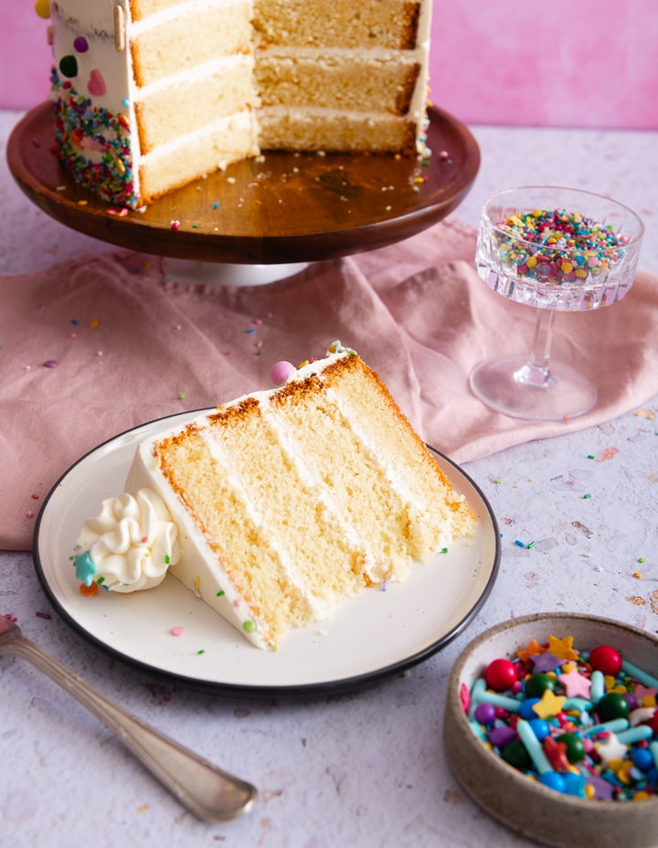 Ein Stück der Buttercreme Geburtstagstorte liegt auf einem Teller vor der Torte.