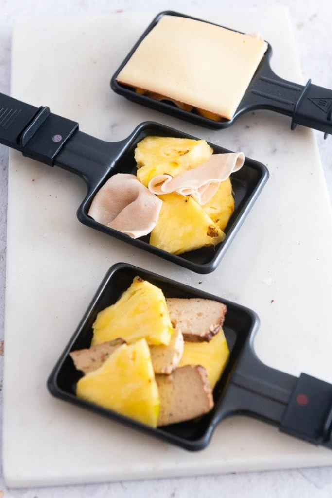 Toast Hawaii Raclette Ideen auf einer Mamorplatte.