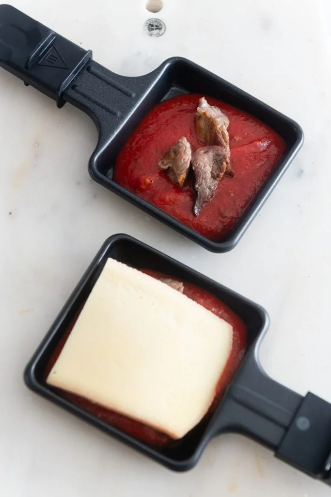 Zartes Rindfleisch mit Tomatensauce & Käse in einem Raclette Pfännchen.