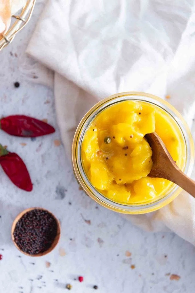 Ein Holzlöffel nimmt etwas von dem indischen Mango-Chutney.