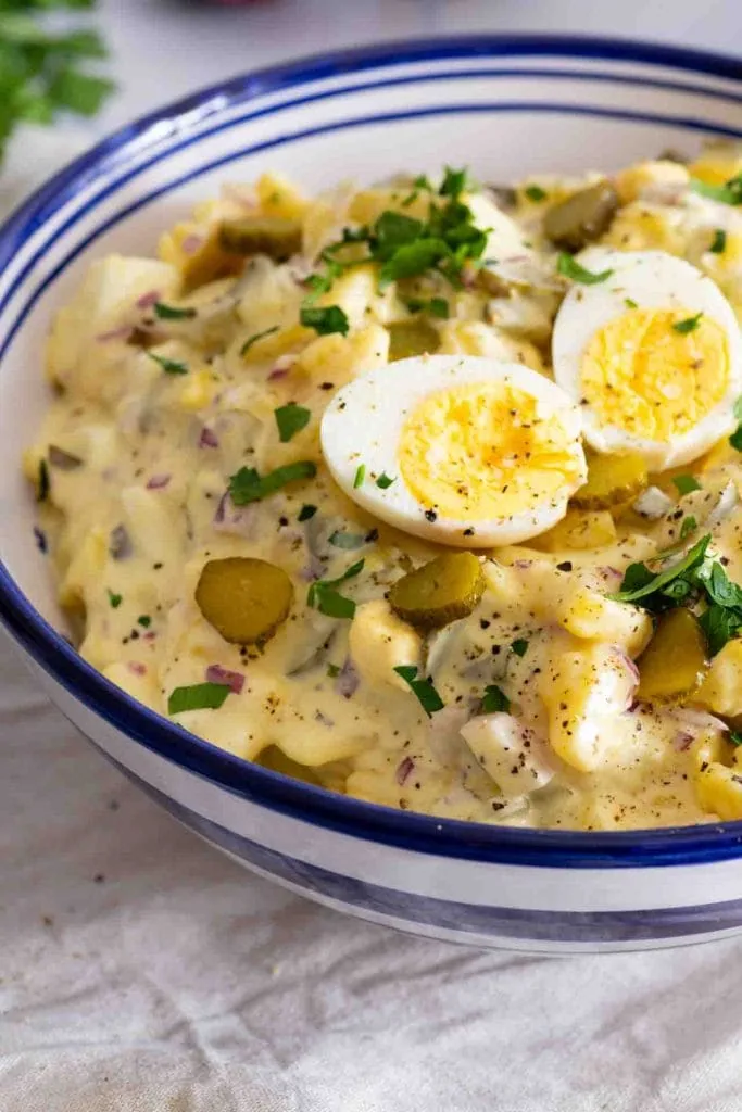 Der fertige Kartoffelsalat mit Mayonnaise in der Nahaufnahme. Man erkennt das zwei Eihälften oben auf liegen.