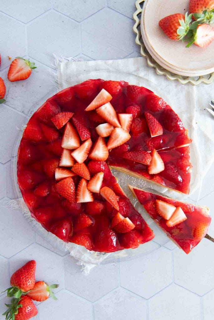 Der fertige Erdbeerkuchen mit Biskuitboden & Vanillepudding. Es wird ein Stück mit einer Kuchengabel genommen.