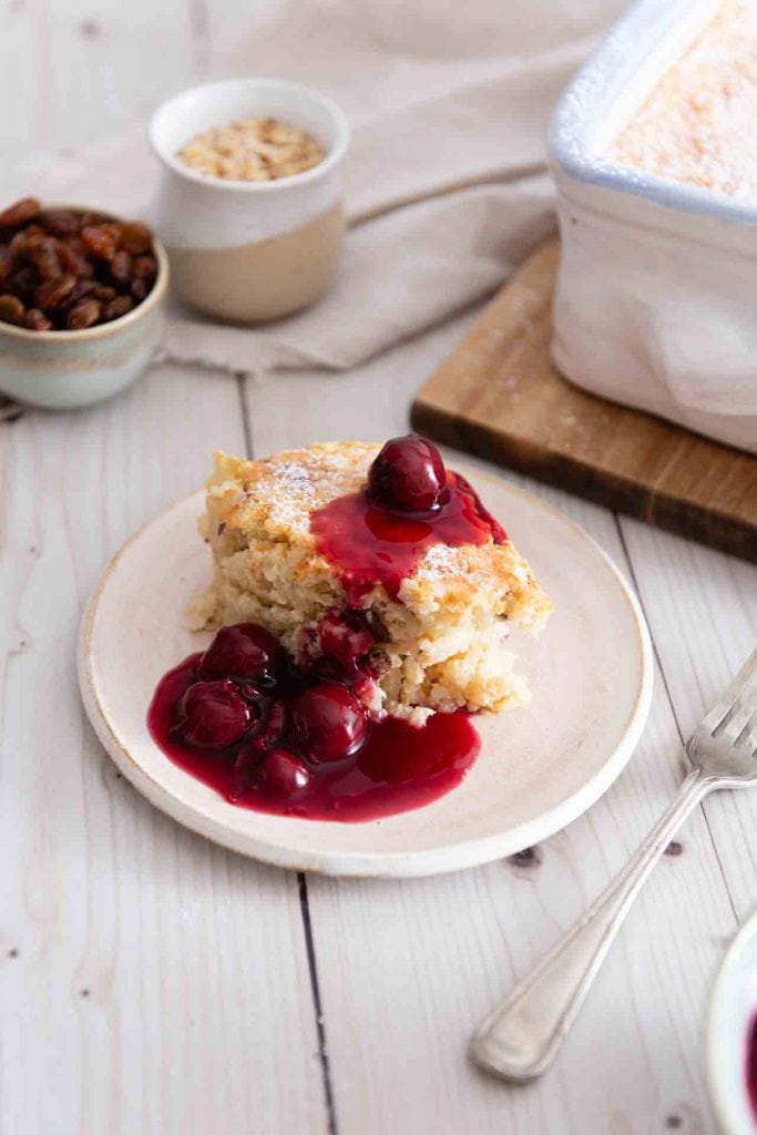 Ein Stück süßer Reisauflauf mit Kirschen und einer Gabel daneben.