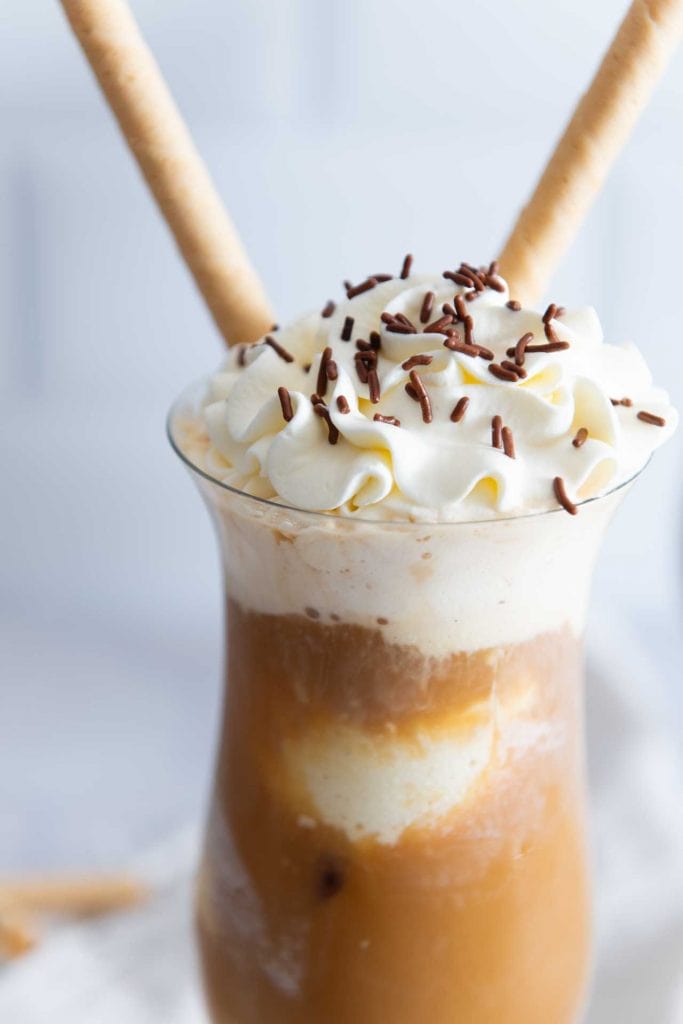 Selbstgemachter Eiskaffee im Glas mit Schlagsahne und zwei Waffeln.