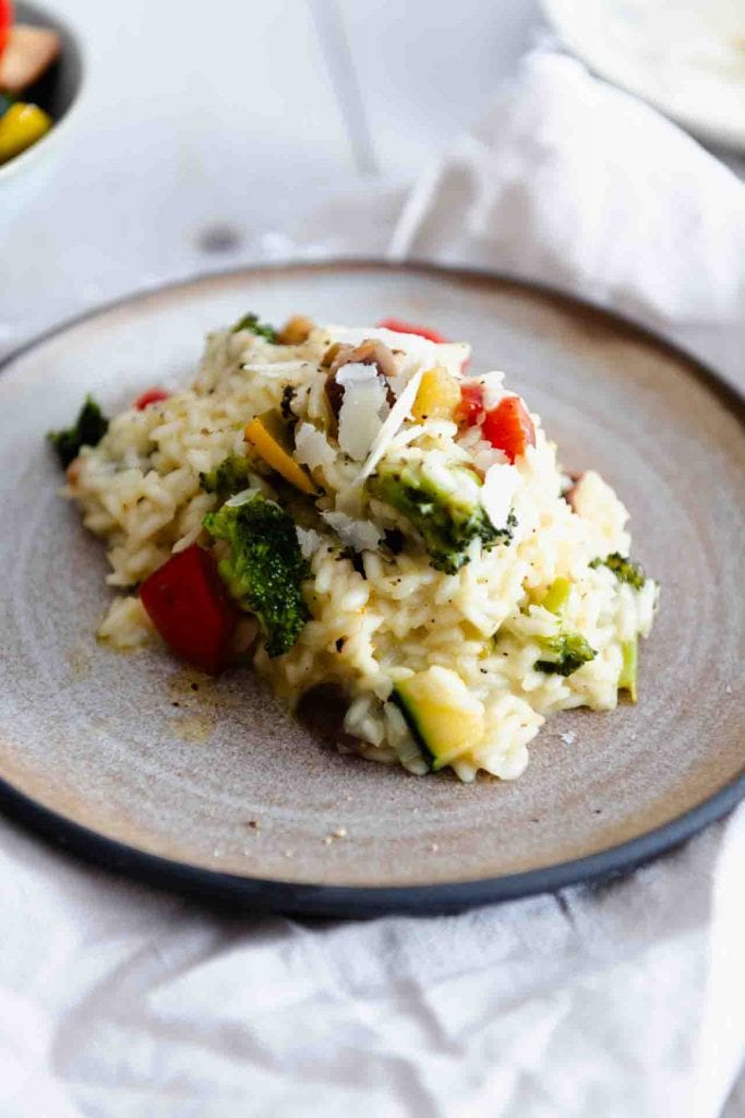 Ein Teller Risotto mit Gemüse und Parmesan auf dem Tisch.
