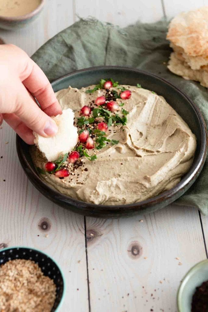 Ein Brot nimmt etwas von dem Aufstrich auf.