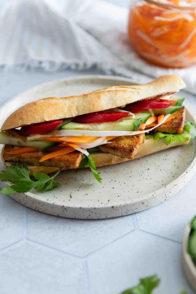 Vietnamesisches Baguette (Banh Mi), vegetarisch belegt mit Tofu, eingelegten Karotten und Daikon (Do Chua), Gurke, Chili und frischem Koriander.
