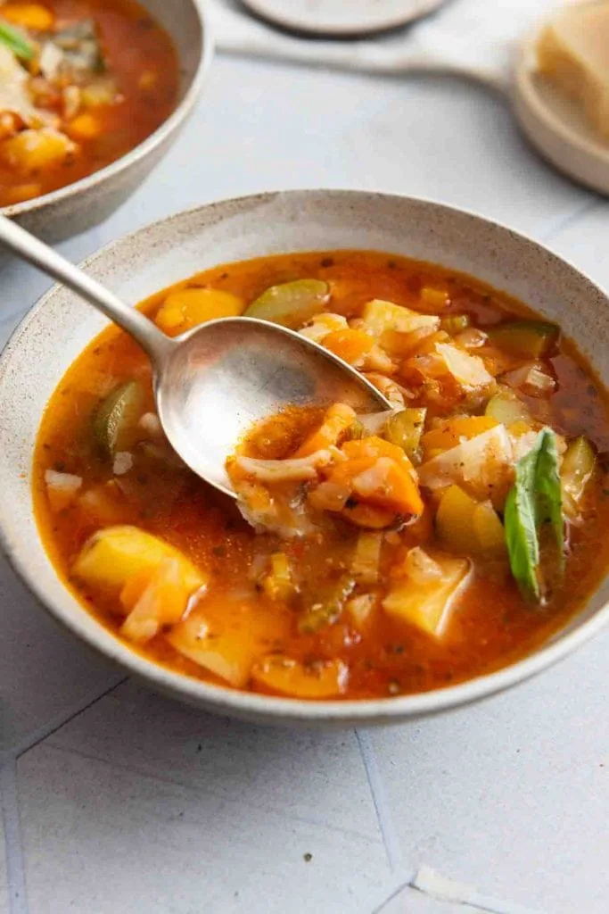 Ein Löffel nimmt etwas von der Minestrone auf.