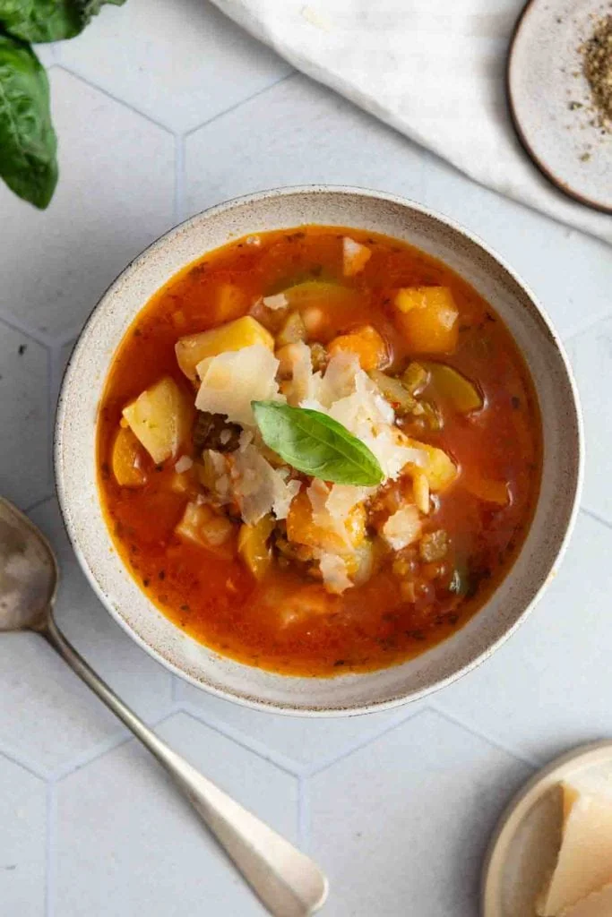 Ein Teller mit der Minestrone vegetarisch, auf dem Tisch.