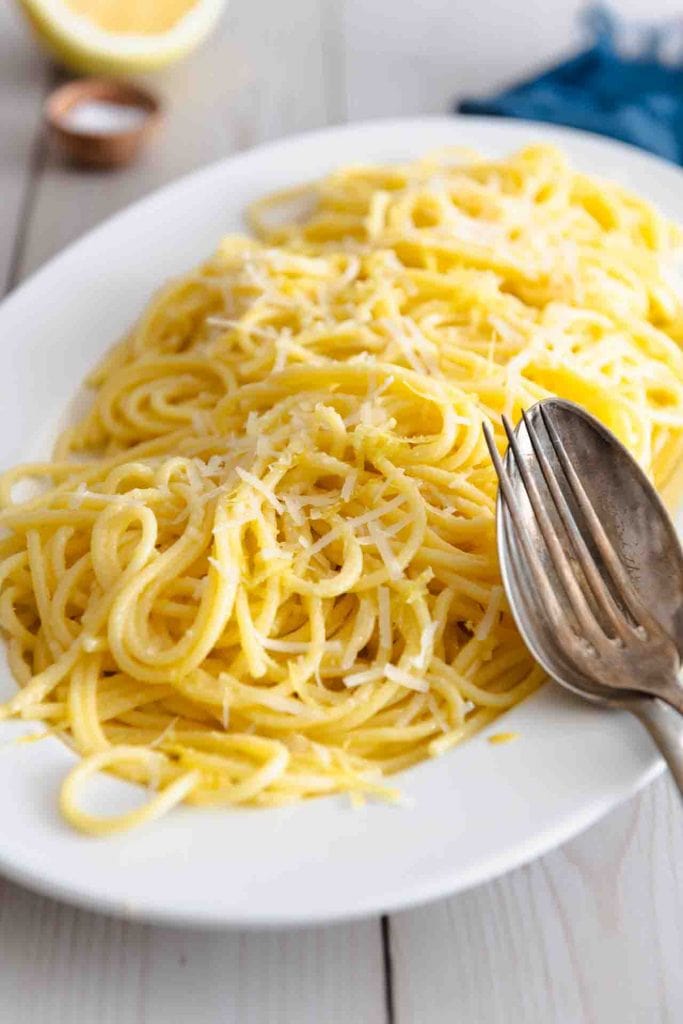 Zitronen Spaghetti italienisch auf einem länglichen Servierteller mit Gabel und Löffel.