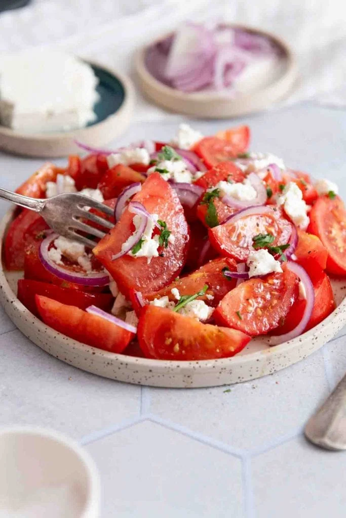 Eine Gabel nimmt Tomatensalat mit Feta auf.