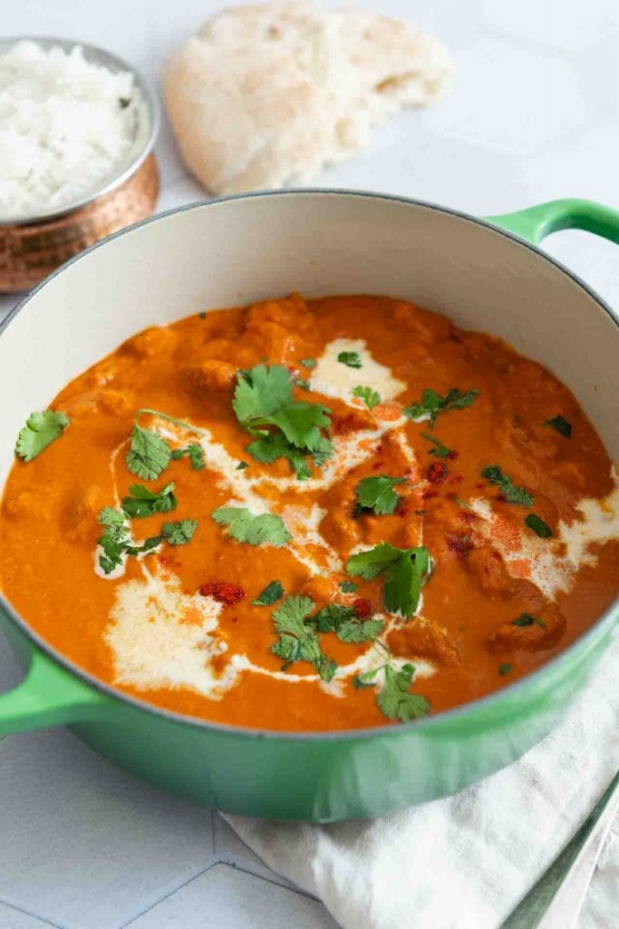 Ein Topf Butter Chicken mit Tofu, neben Reis und Naan.