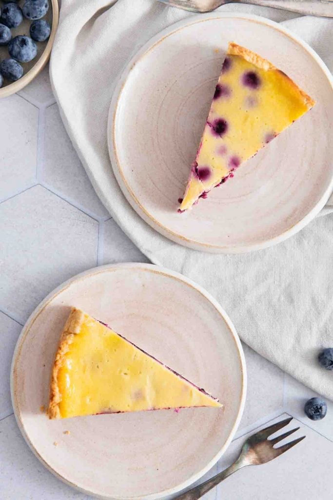 Zwei Stücke Blaubeerkuchen mit Schmand auf dem Tisch.