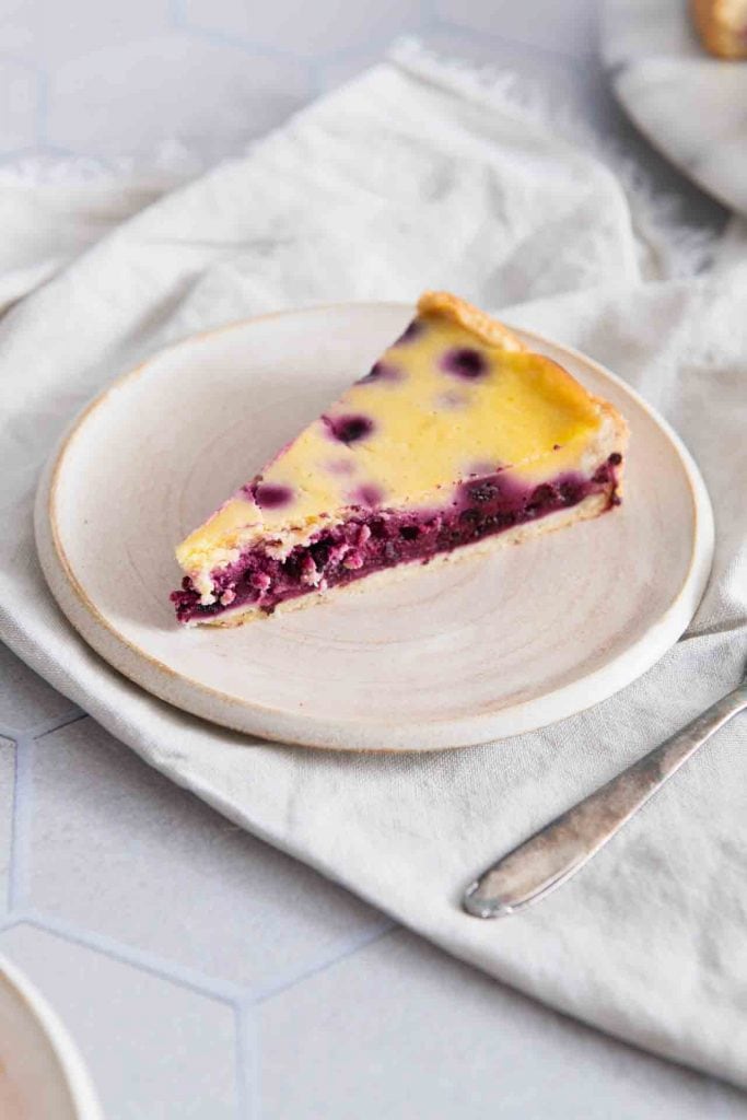 Ein Stück Heidelbeer-Schmand-Kuchen aus Mürbeteig auf dem Teller.