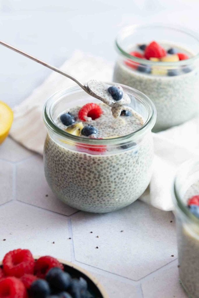 Ein Löffel nimmt etwas Chia Pudding auf und eine Blaubeere dazu.