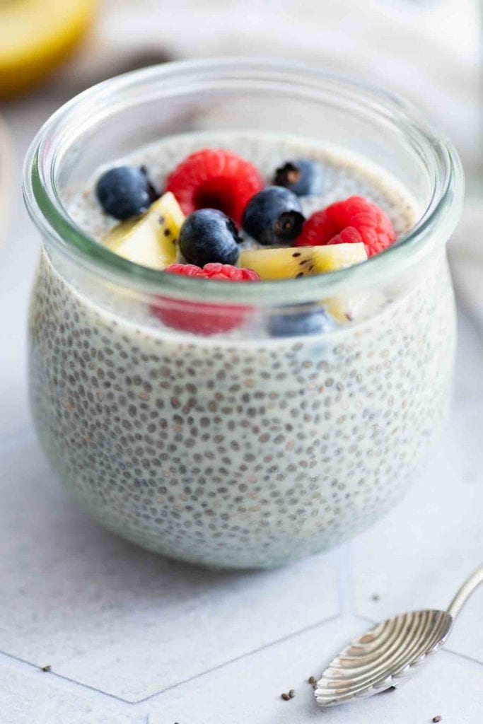 Ein Chia Pudding mit Milch und einem kleinen Löffel daneben.