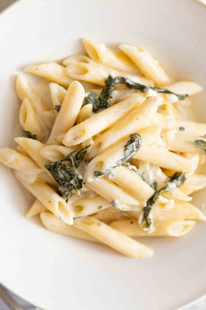 Penne Nudeln in cremiger Gorgonzola-Spinat-Soße in einer weißen Schale.
