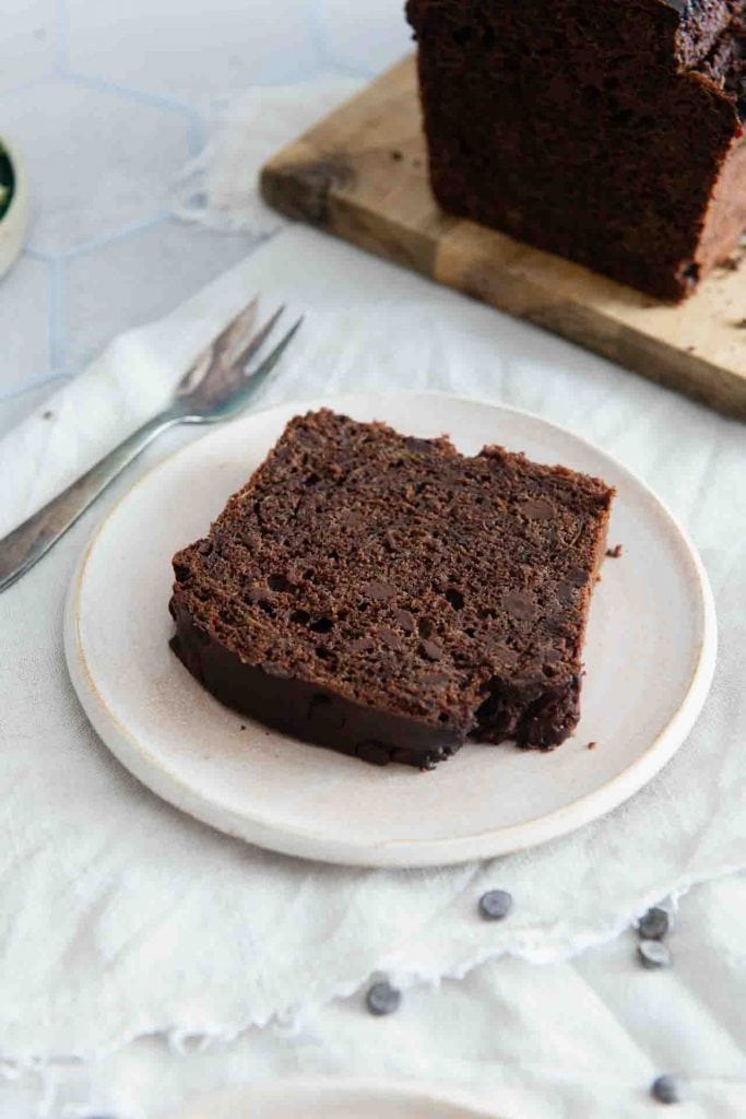 Ein Stück saftigen Zucchini Schoko Kuchen mit einer kleinen Gabel daneben.