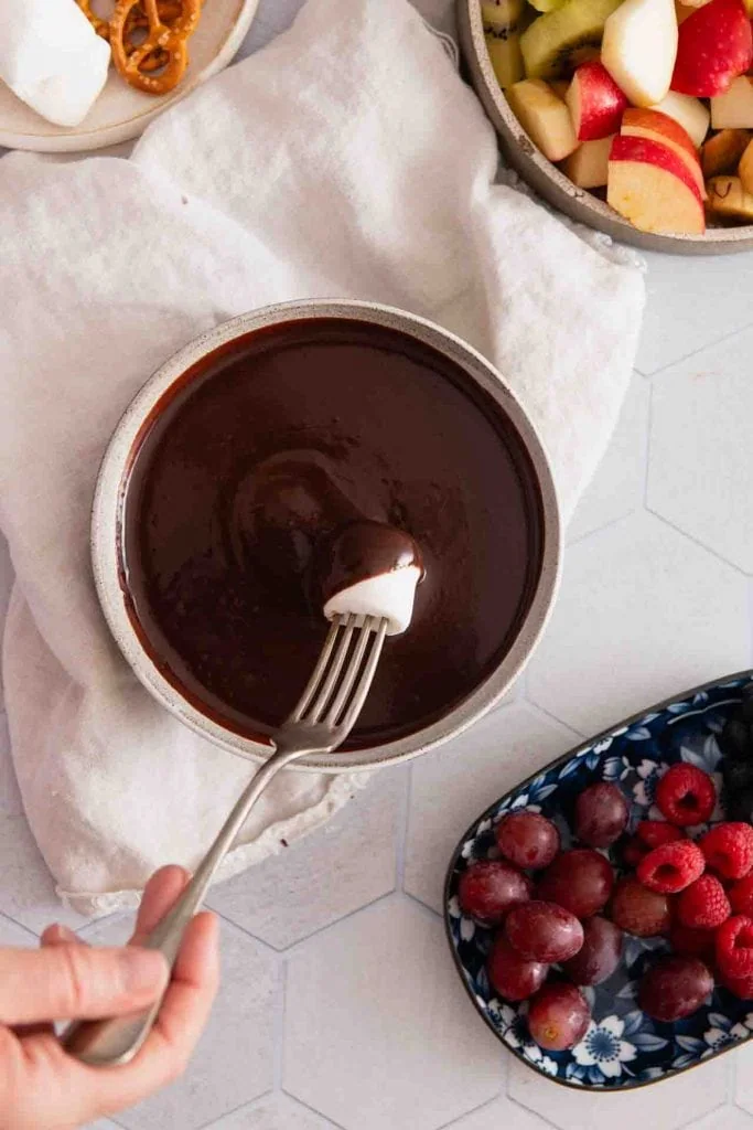 In das Schokofondue wird ein Marshmallow eingetaucht.