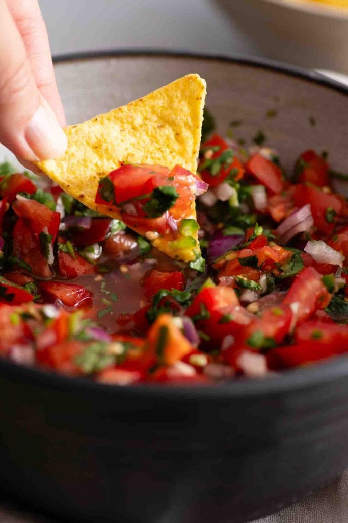 Ein Nacho nimmt Pico de Gallo auf