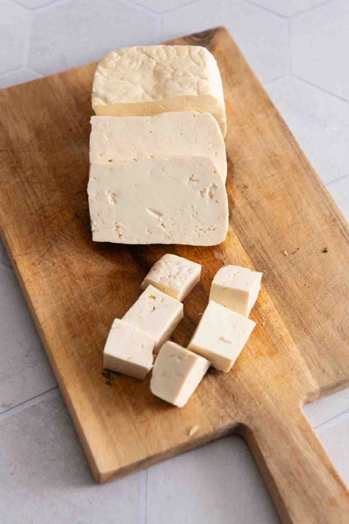 Ein Block frischer, weicher Seidentofu (Natur) auf einem kleinen, rustikalen Holzbrettchen, bereit zur Verwendung.