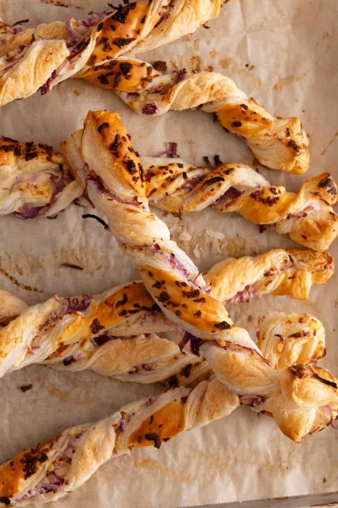 Zwiebelstangen mit Blätterteig auf einem Blech.