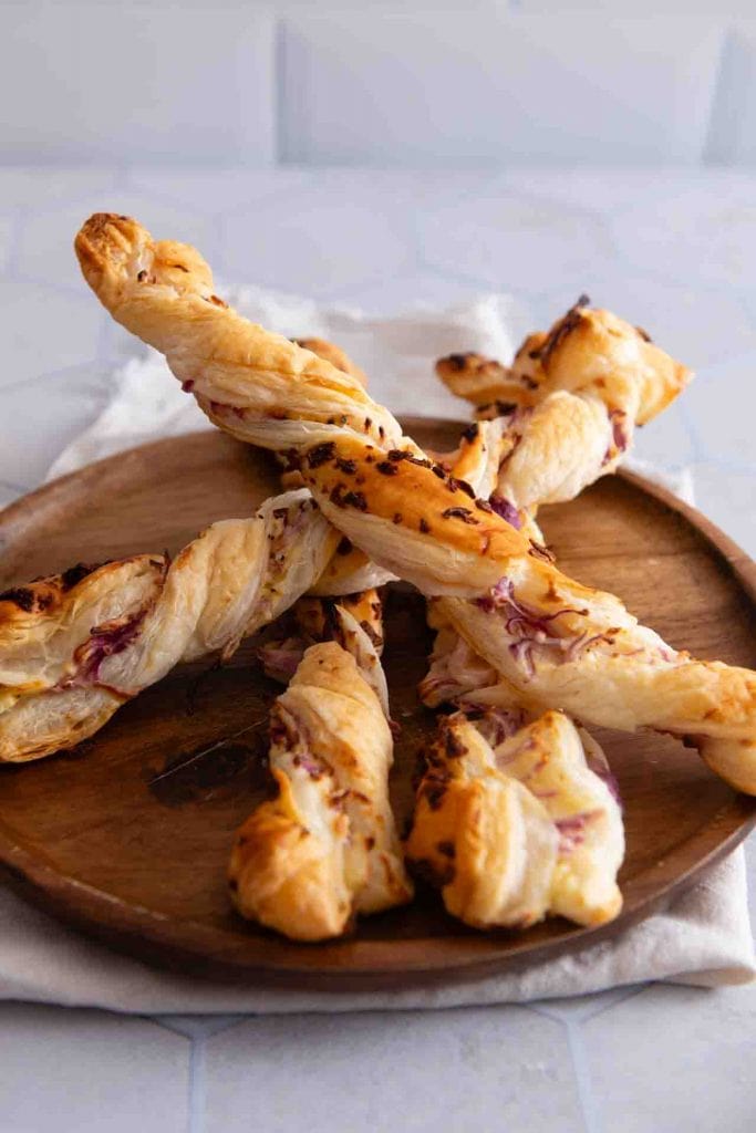 Blätterteigstangen mit Frischkäse auf einem Holzteller.