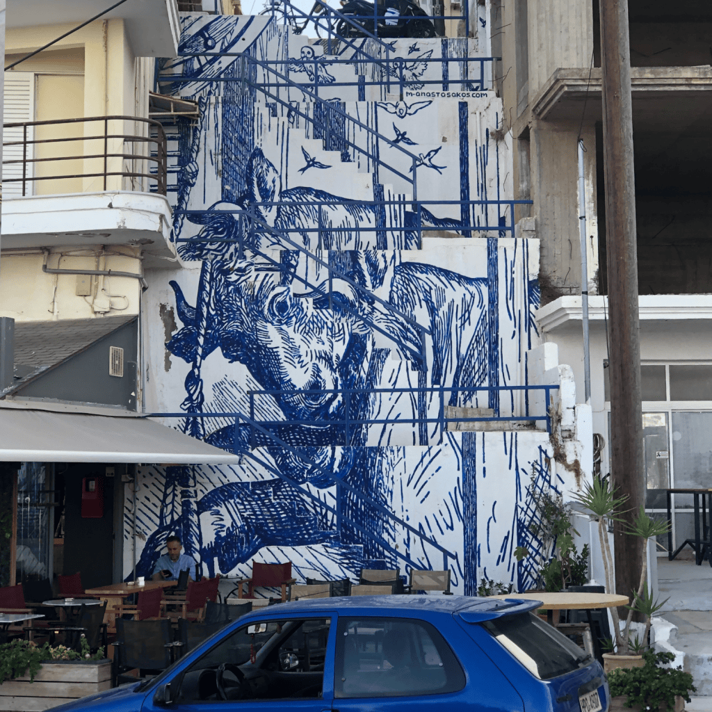 Ein Hausgemälde in Kreta in blau mit einem blauen Auto davor.