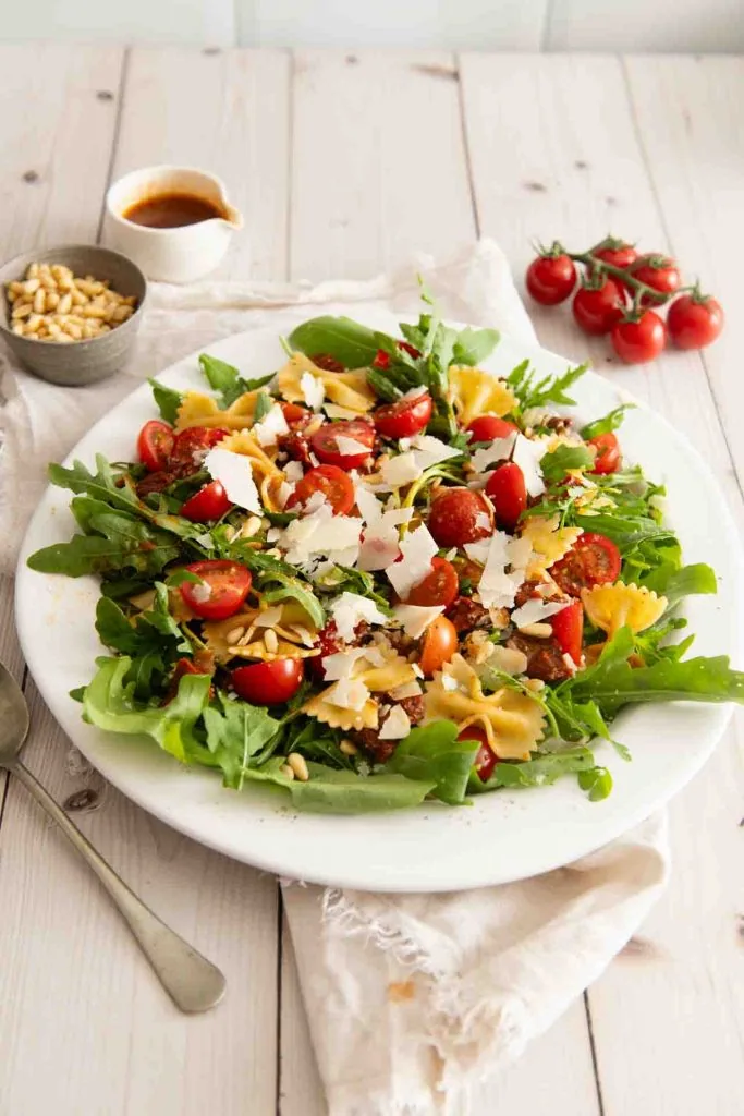 Ein Salat mit Rucola, getrocknete Tomaten, Parmesan und Pinienkerne