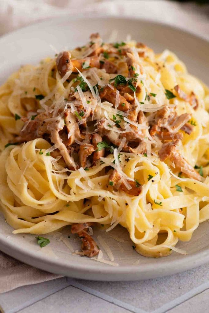 Die fertige Pfifferling Pasta serviert auf einem Teller mit Parmesan
