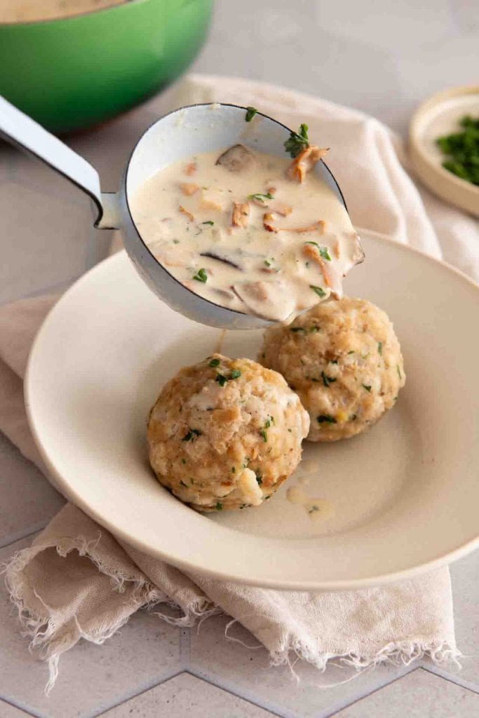 Rahmschwammerl mit Semmelknödel werden in einen Teller gegeben.