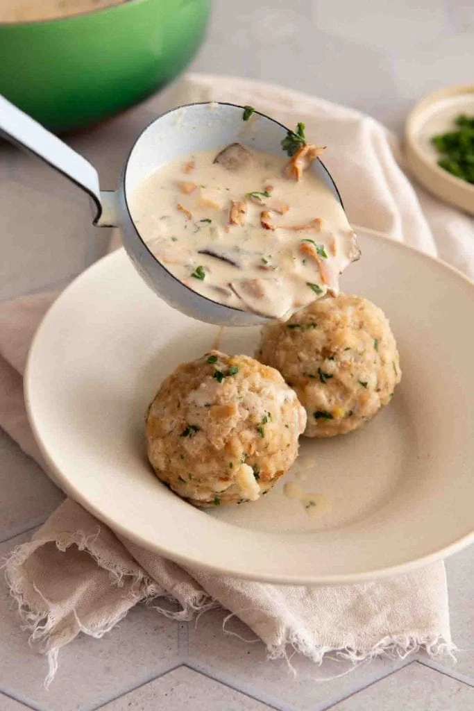 Rahmschwammerl mit Semmelknödel werden in einen Teller gegeben.