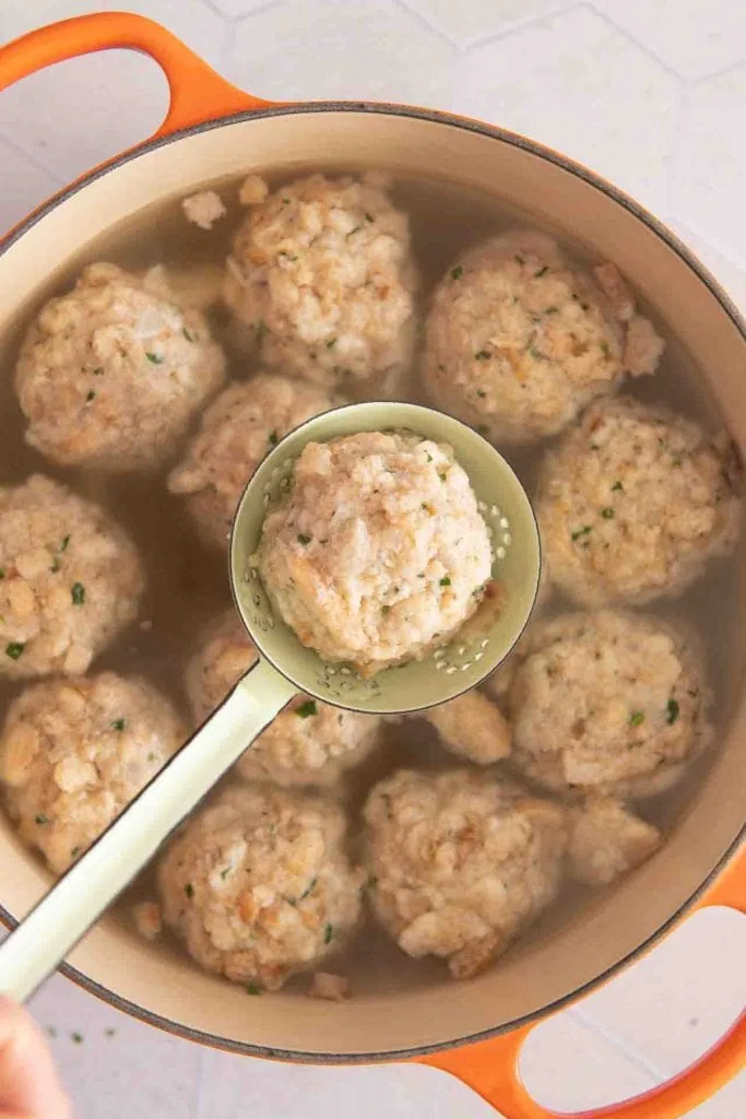 Ein Semmelknödel wird aus dem Topf geholt