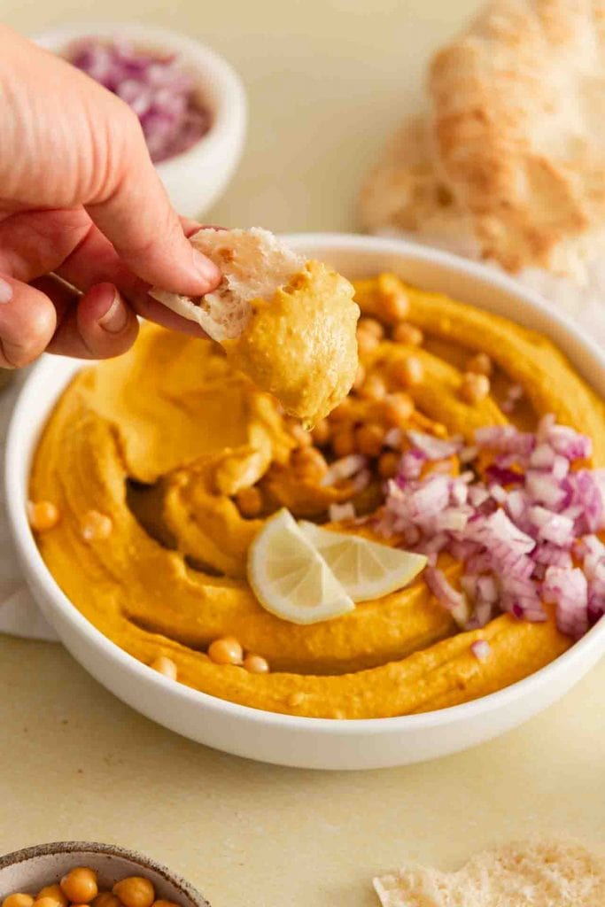Ein Stück Fladen nimmt etwas von dem Hummus auf.