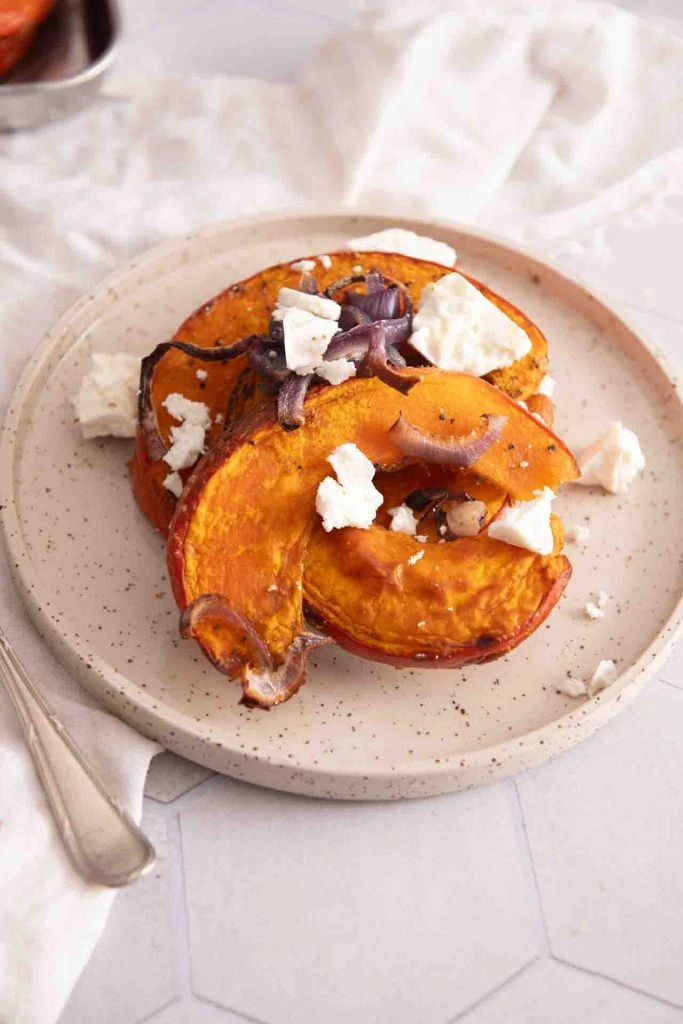 Der Kürbis mit Feta und Zwiebel auf einem Teller.